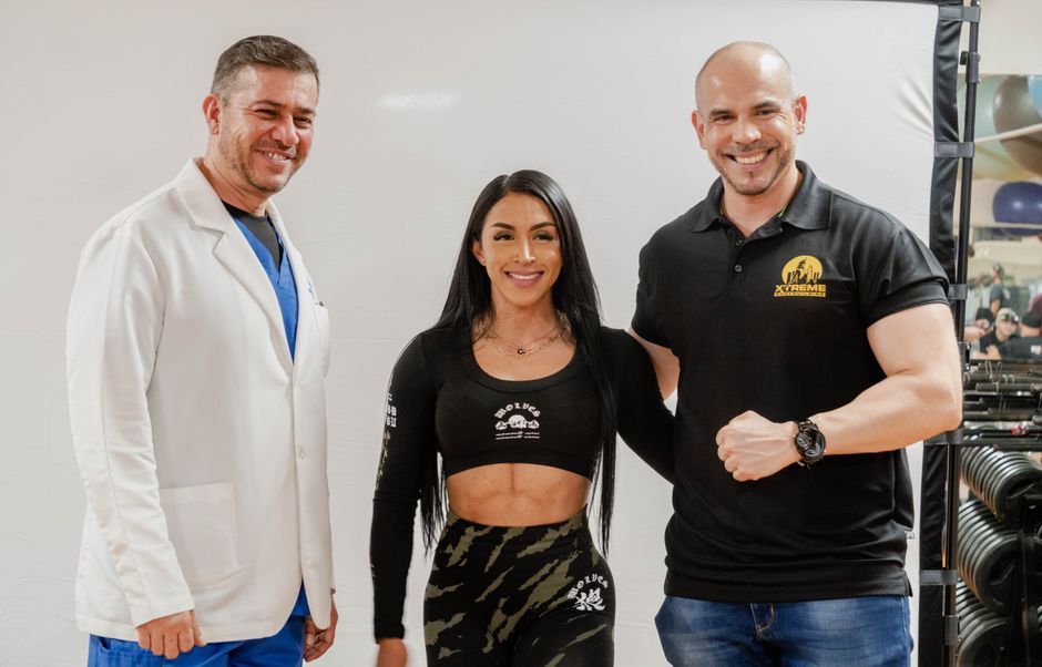 Three people smiling and standing in a fitness studio, capturing a friendly and energetic moment.